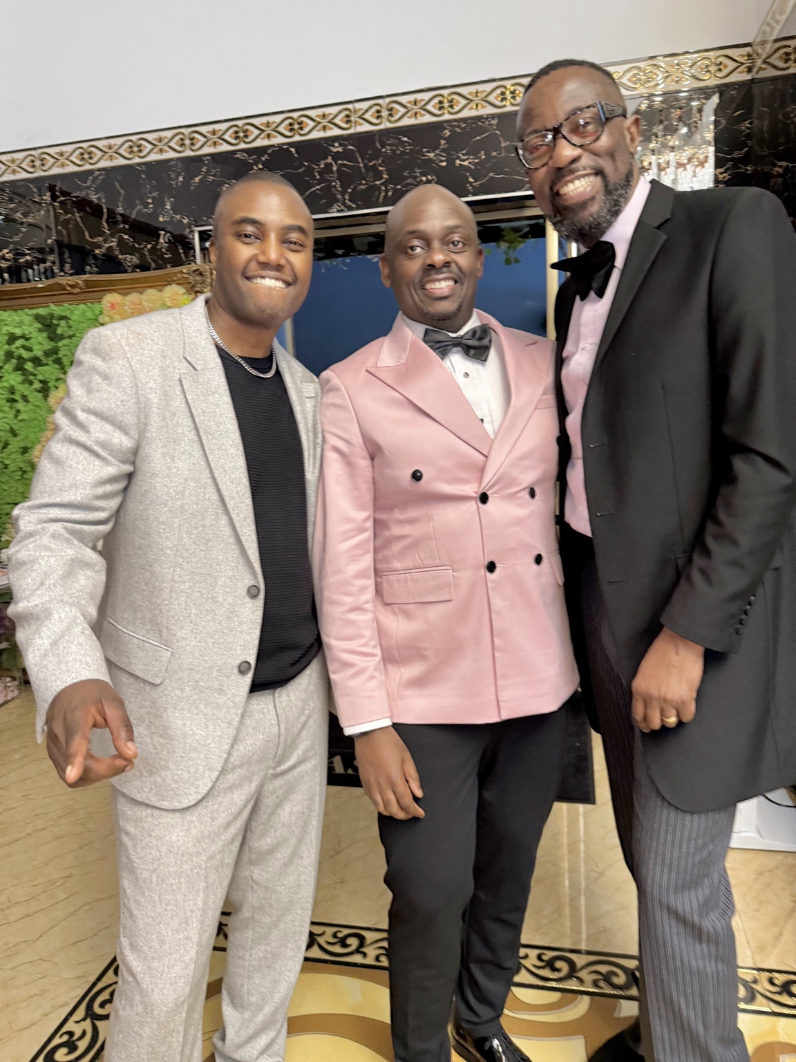 Three guests posing together in formal evening wear at the 2024 Grille Community Christmas Gala