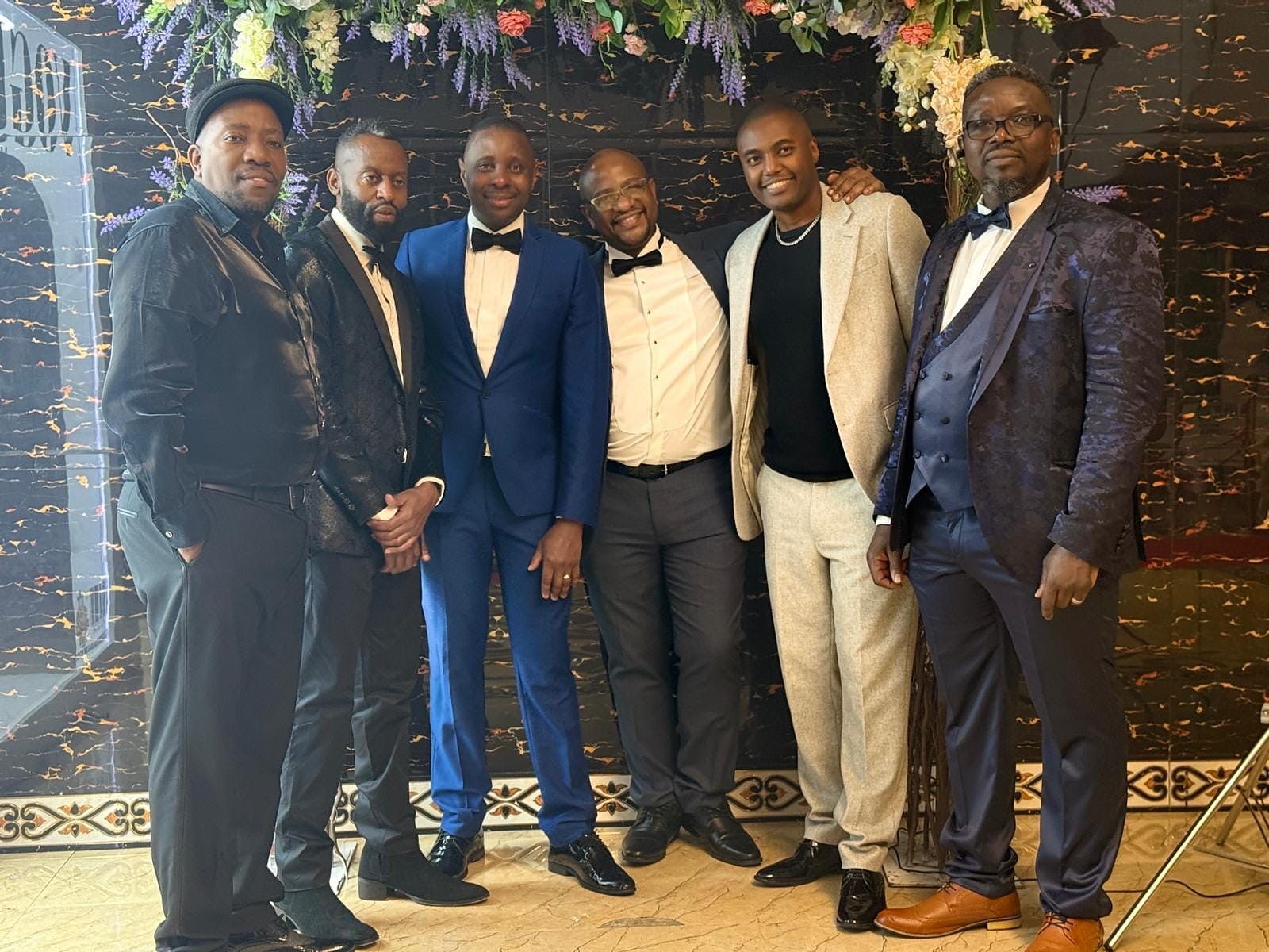 A group of elegantly dressed guests posing together at the 2024 Grille Community Christmas Gala