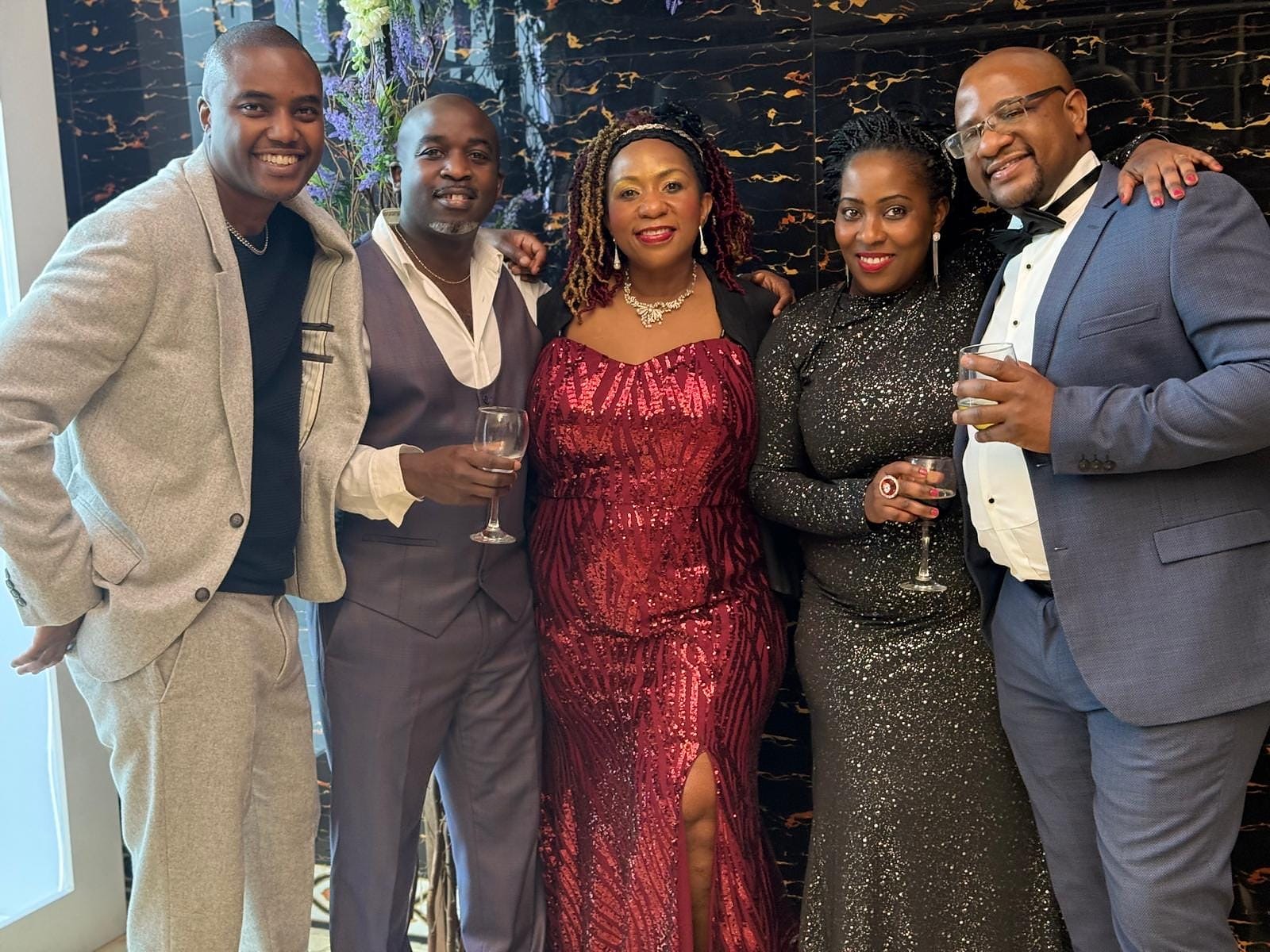 Friends posing together in formal evening wear at the 2024 Grille Community Christmas Gala