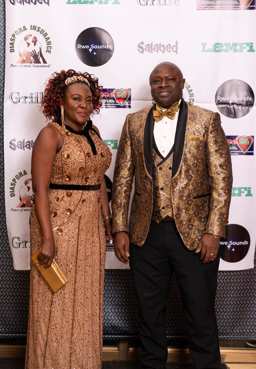 A couple posing against the Grille gala backdrop at the 2024 Grille Community Christmas Gala